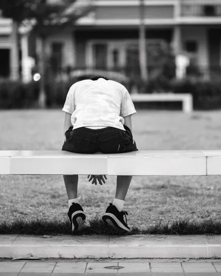 The child was sitting in a sad square chair at a park. This is a
