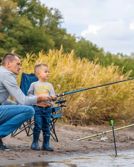 A happy family spends time together they teach their son to fish.