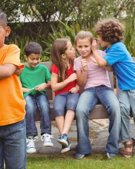 Upset child standing away from group sitting on a bench