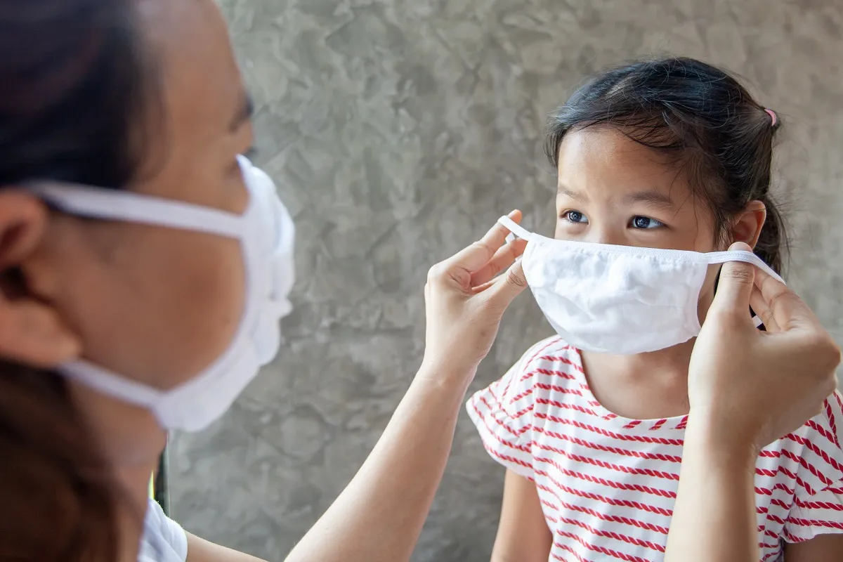 Asian mother help her daughter wearing protection mask to protec