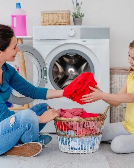 Mother with daughter near washing machine