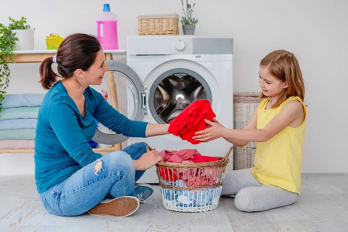 Mother with daughter near washing machine