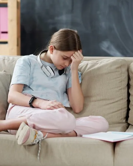Sad teenage girl with books being upset because of self isolation at home