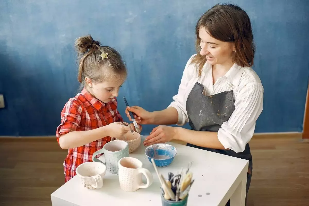 A woman with child makes dishes in a pottery