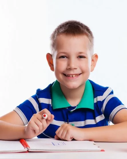 Cute schoolboy is writting isolated on a white background