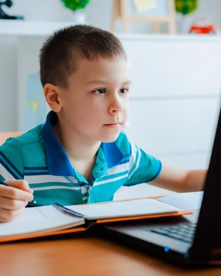 Distance learning online education. A schoolboy boy studies at home and does school homework. A home distance learning