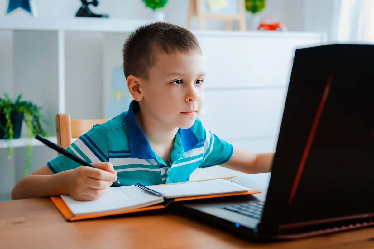 Distance learning online education. A schoolboy boy studies at home and does school homework. A home distance learning