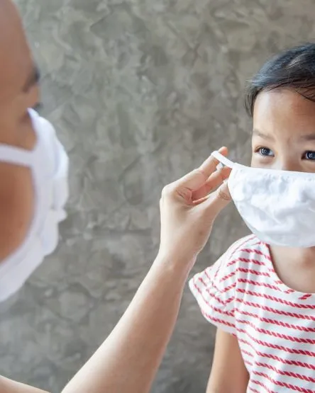 Asian mother help her daughter wearing protection mask to protec