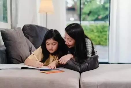Asian middle-aged woman teach her daughter do homework and drawi