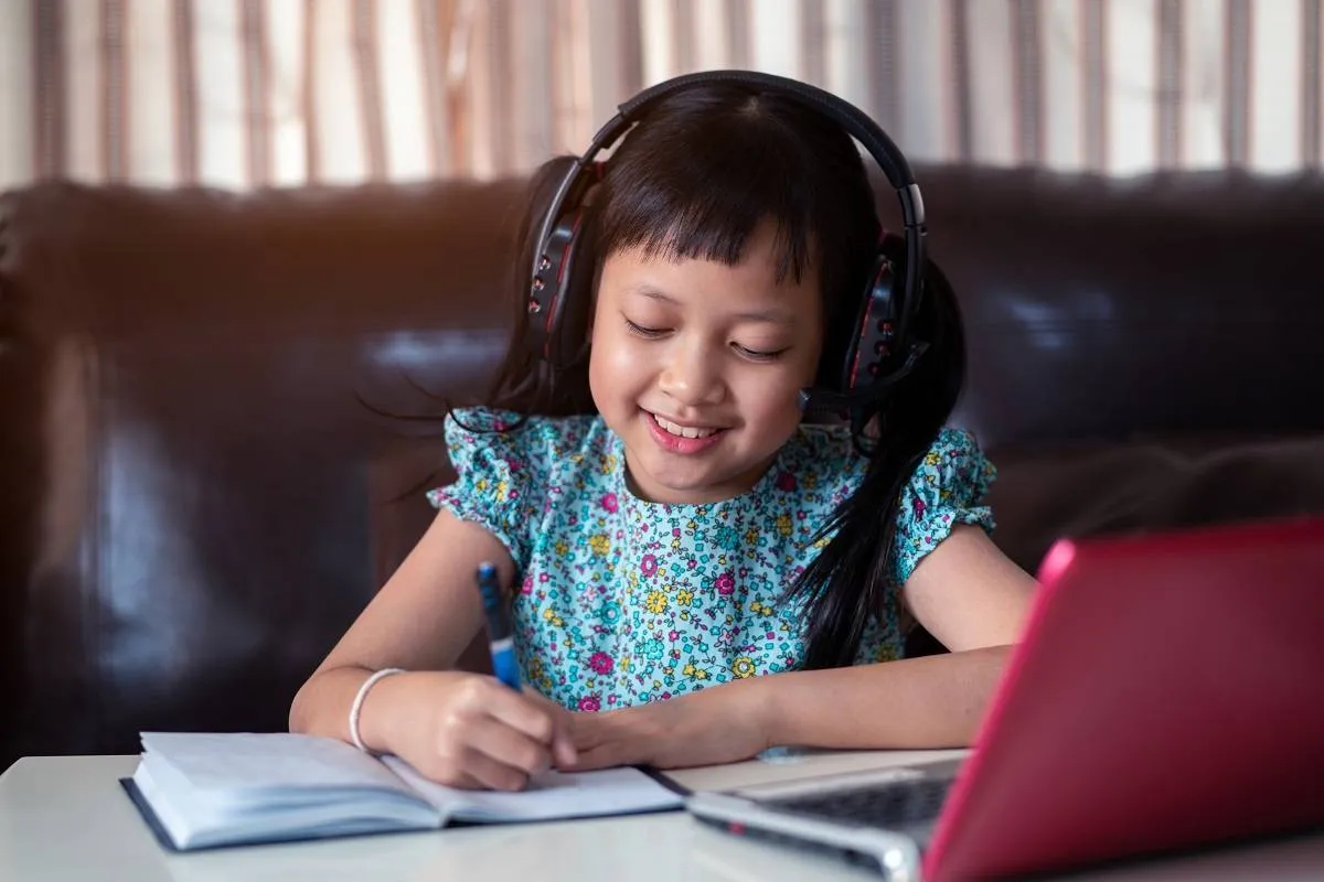Cute asian little child girl studying online lesson at home, so