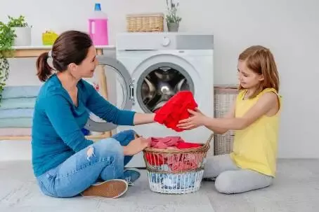 Mother with daughter near washing machine