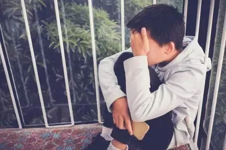 Young Asian preteen teenager boy hugging his knee and cover his