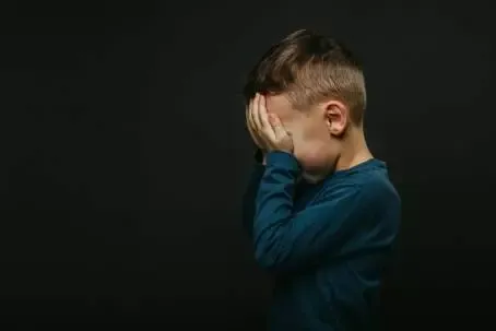 a child whose depression is on a black background with his hands