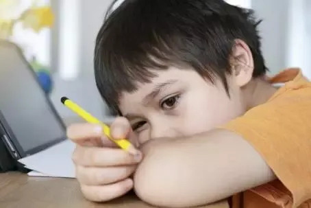 Schoolkid in self isolation using tablet for his homework,Bored